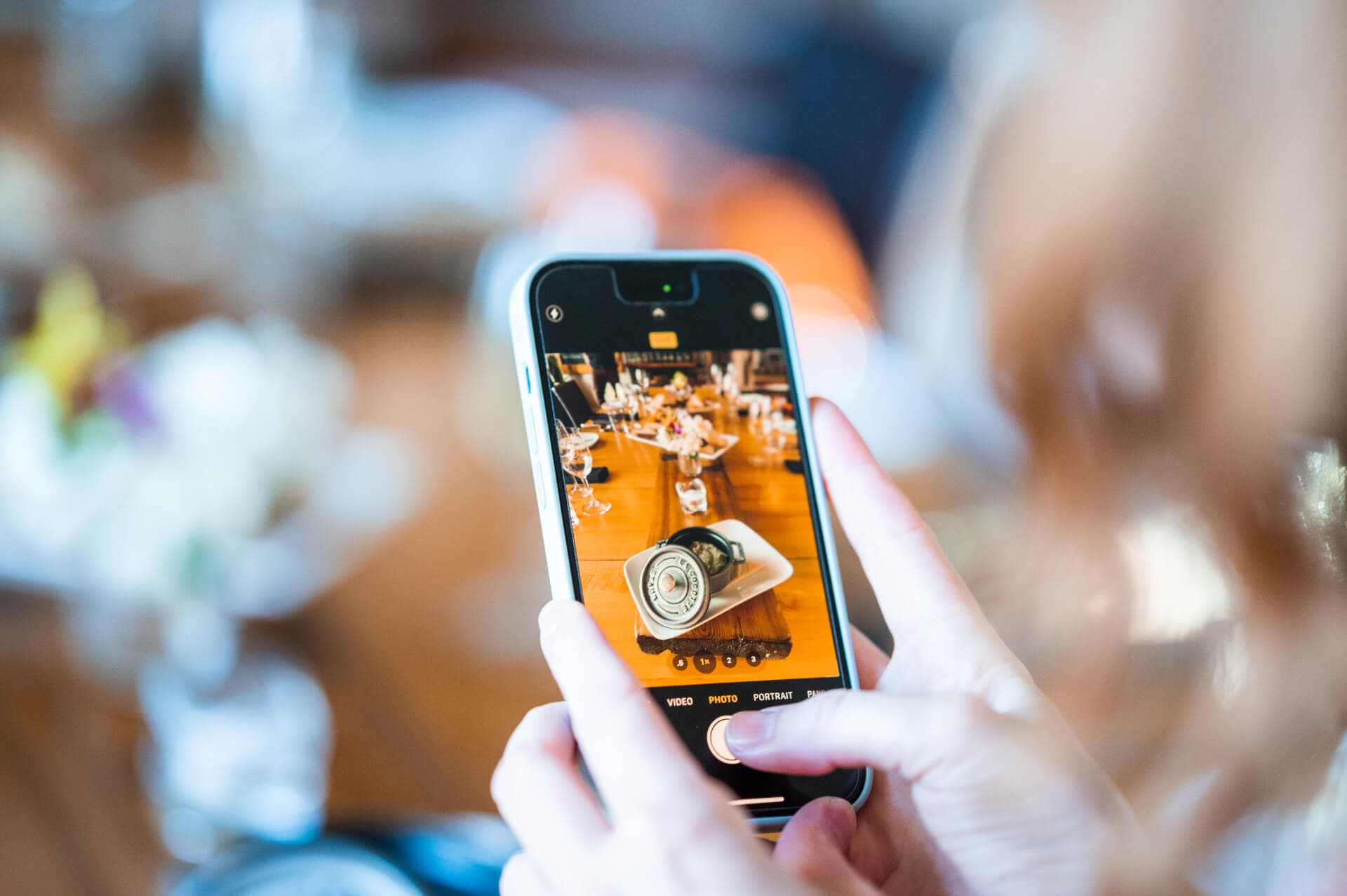 A content creator photographing a restaurant table on their phone
